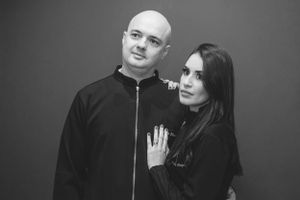 Artistic black and white photo of couple in dark clothing posing together.