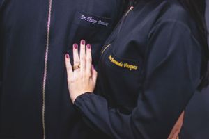Close-up of hand touching embroidered medical uniform in dark blue.