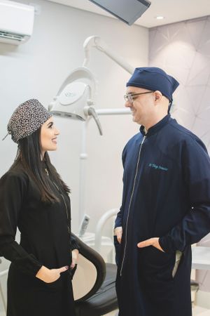 Medical professionals in scrubs having a discussion in a modern dental office with equipment visible in background.
