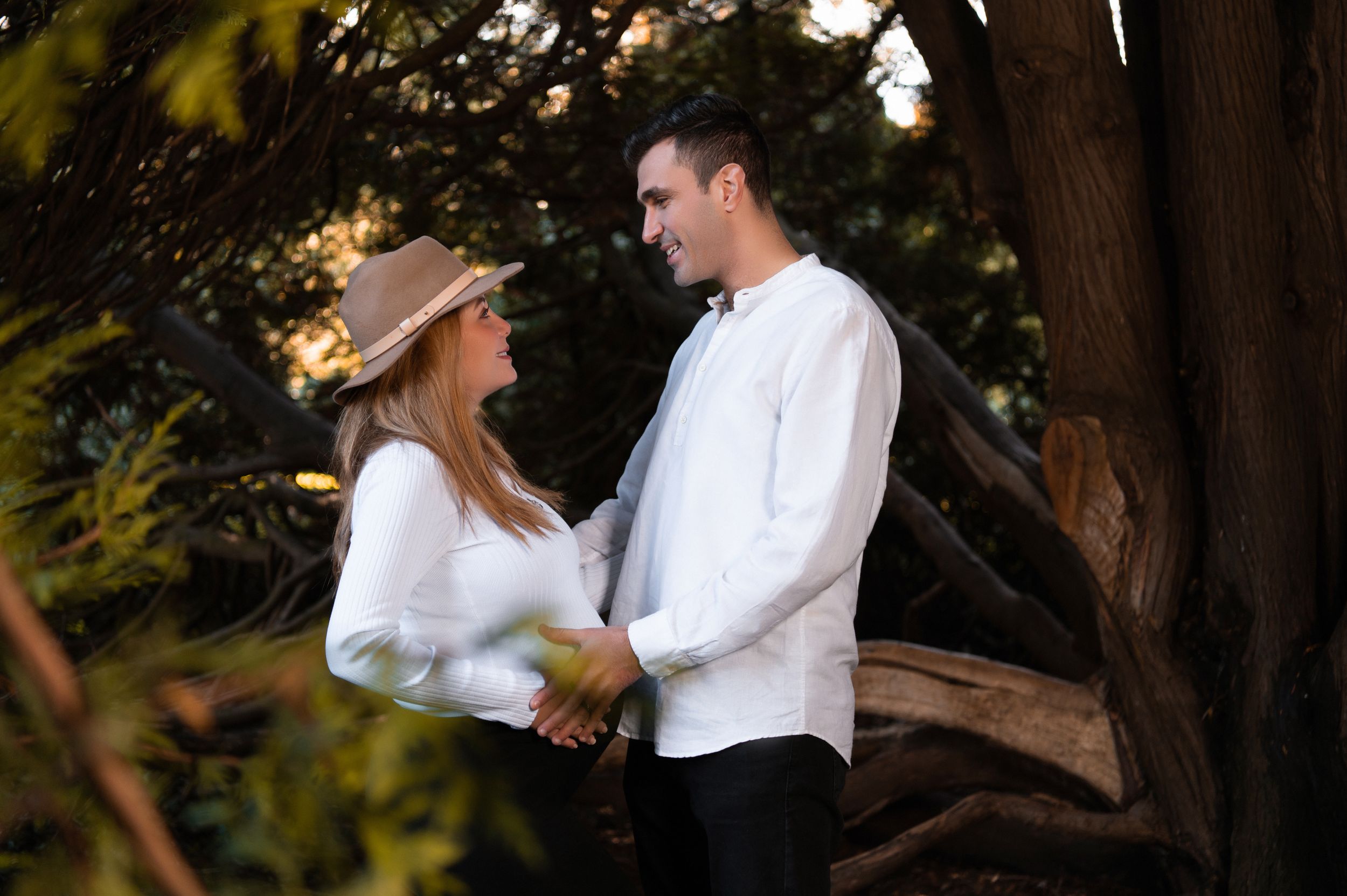 Romantic couple portrait session under trees in white outfits.