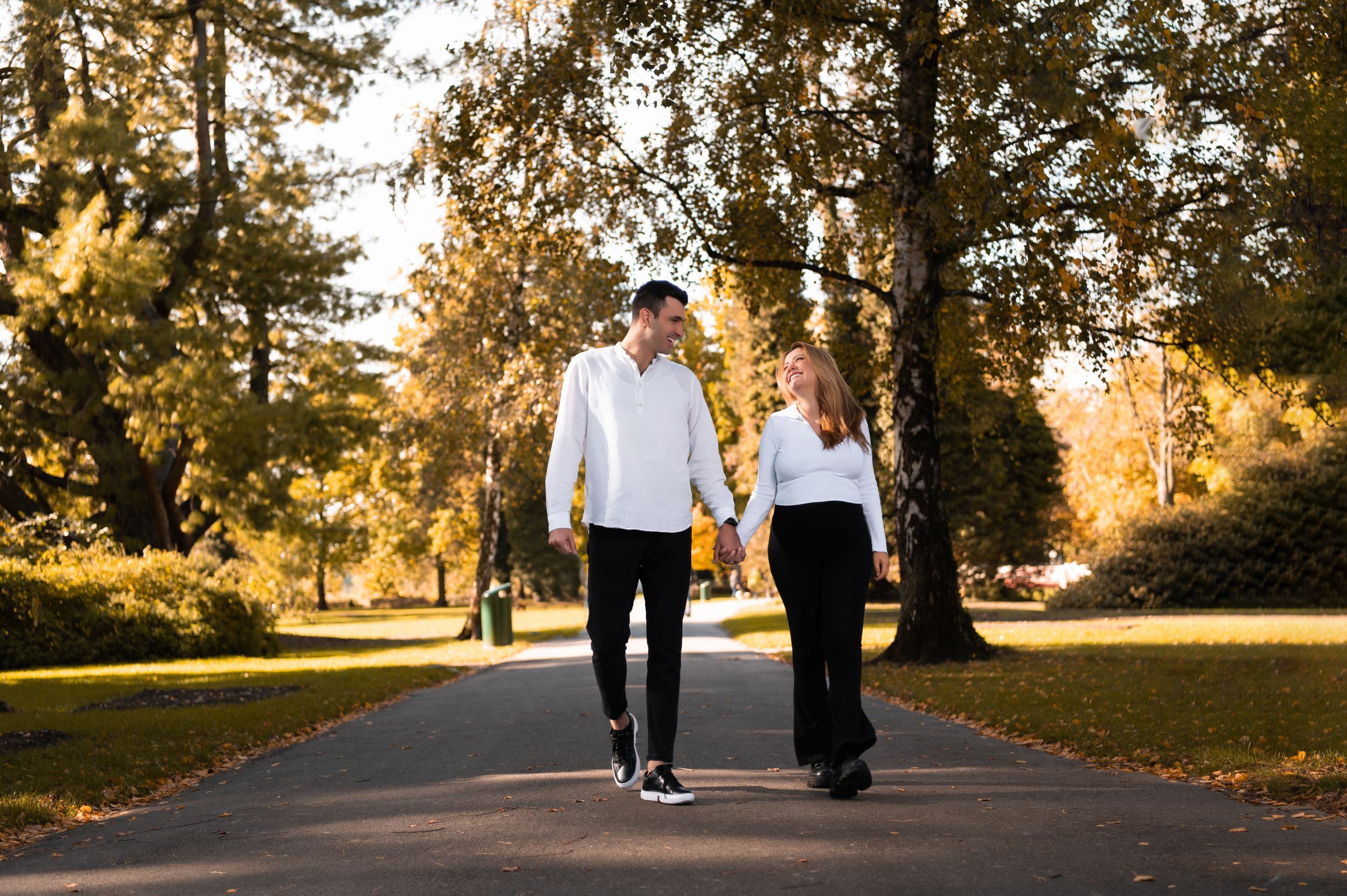 Couple walking together on a tree-lined path during golden hour sunset.