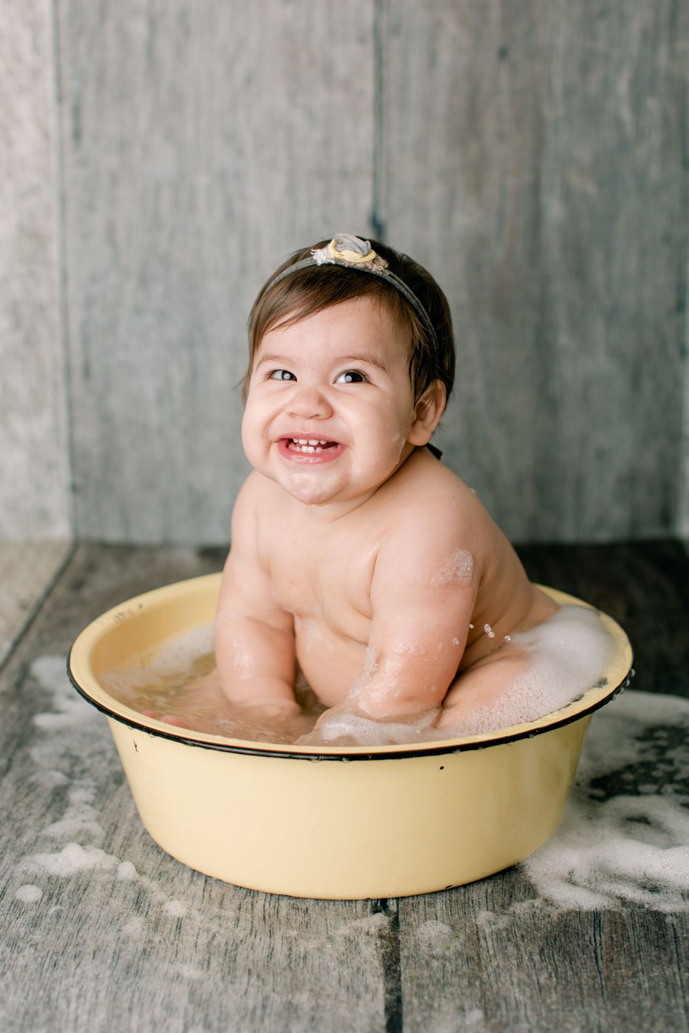 Sweet candid moment during bath time in yellow vintage tub with rustic setting.