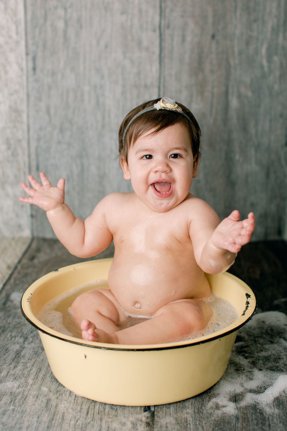 Enthusiastic bath time moment with raised arms in vintage yellow tub.