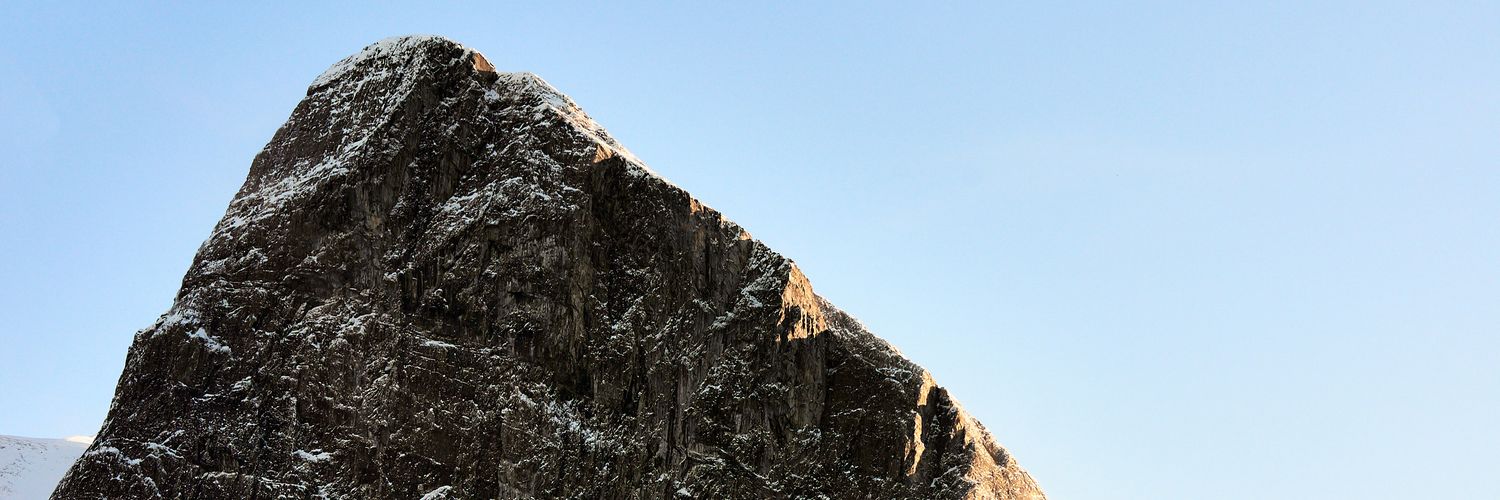 A snow covered mountain peak, with a touch of sun.