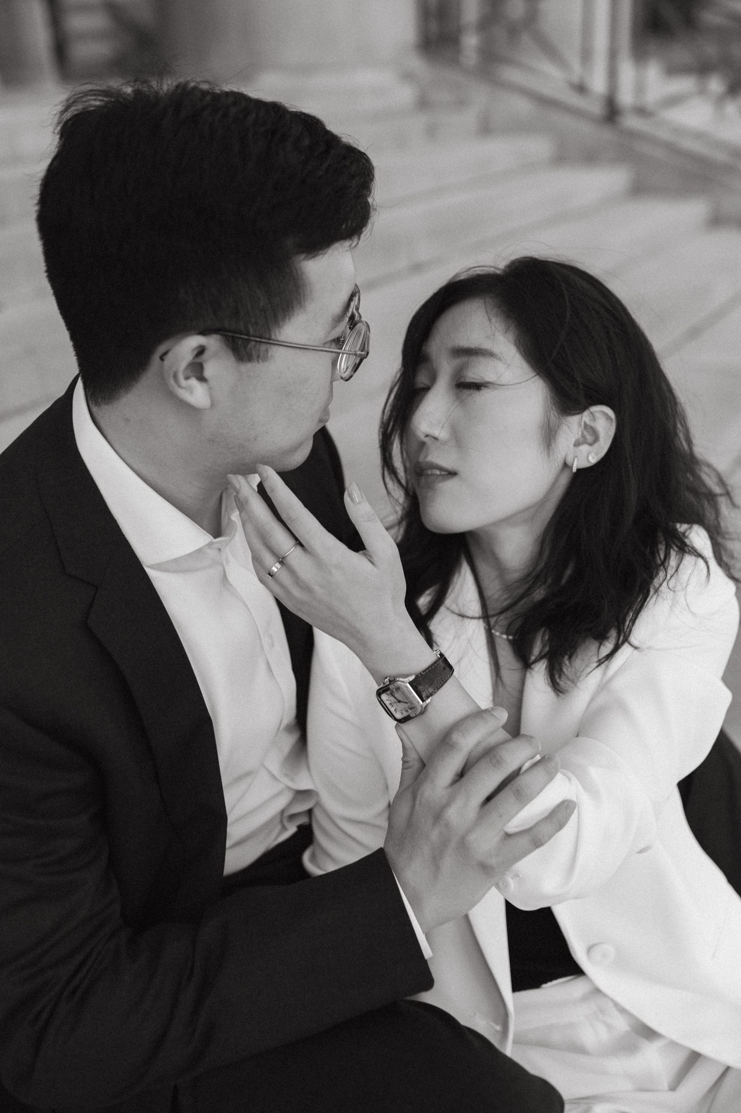 Black and white portrait of an intimate moment between two people in formal attire.