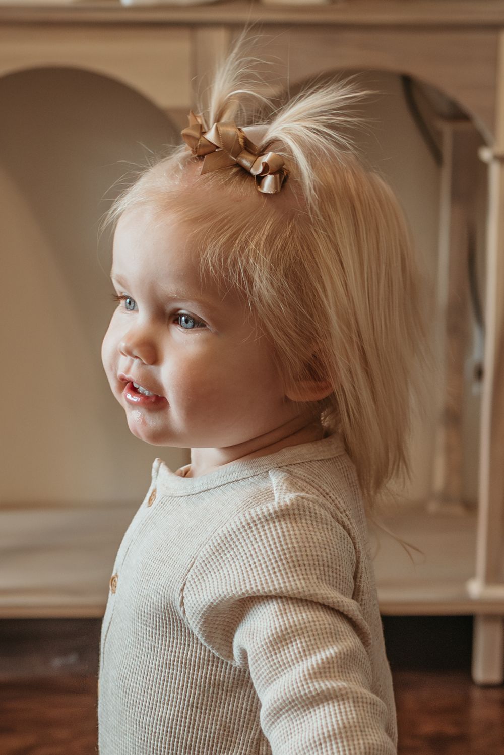 Profile views of a child in a cream knit sweater against neutral indoor background.