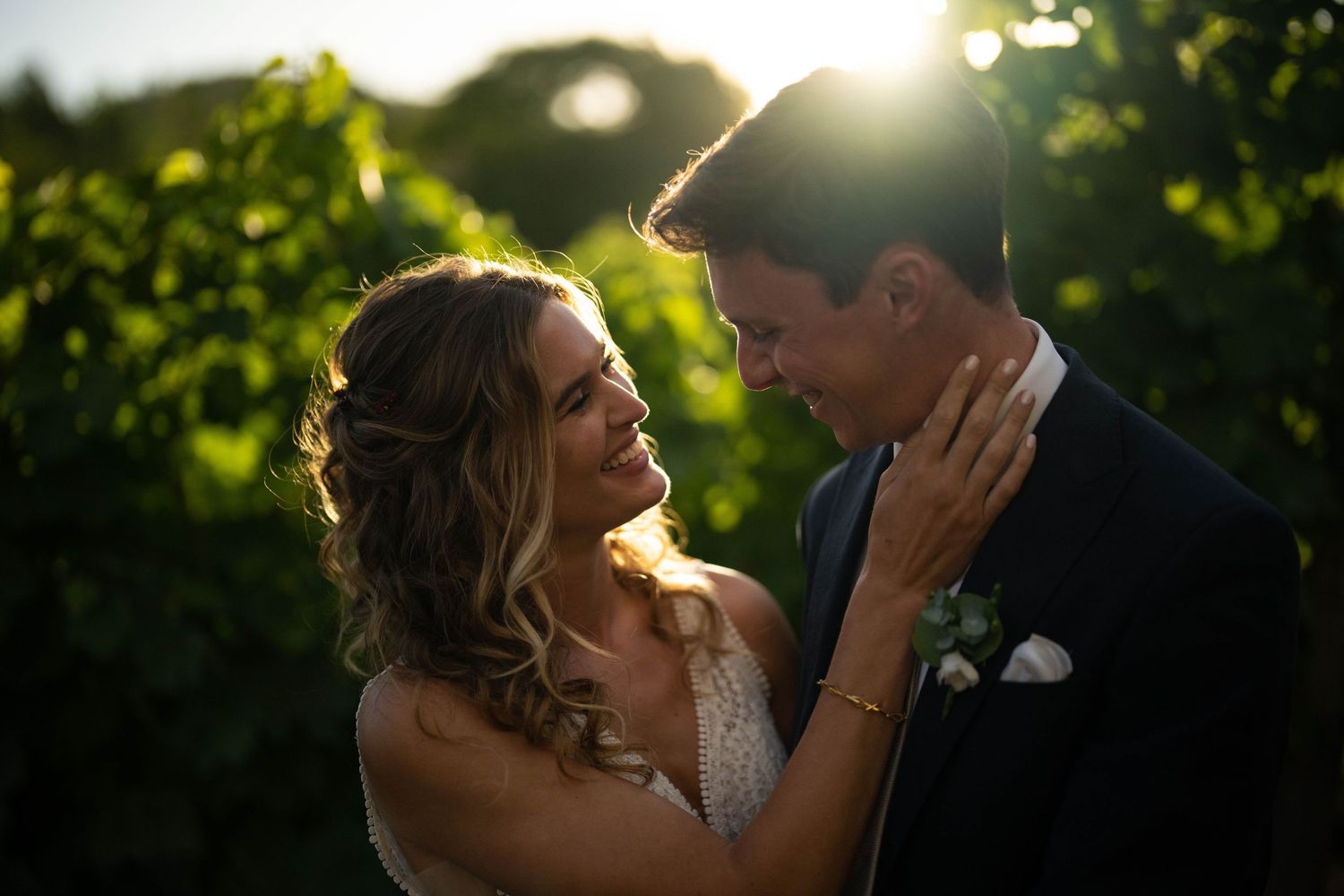 Bride and groom embrace in a vineyard at sunset