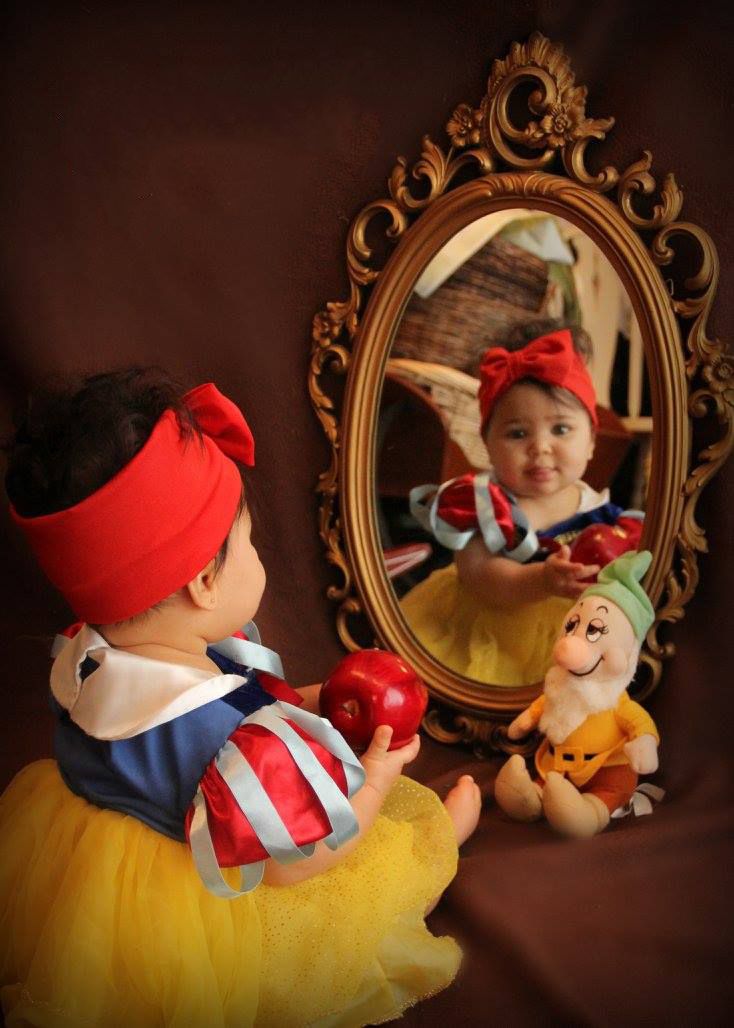 Fairy tale themed photo with ornate mirror and stuffed dwarf toy.