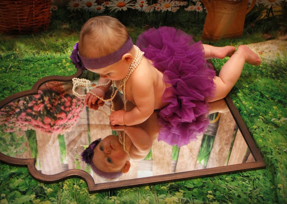 A creative photo with a purple tutu costume and mirror reflection in an outdoor garden setting.