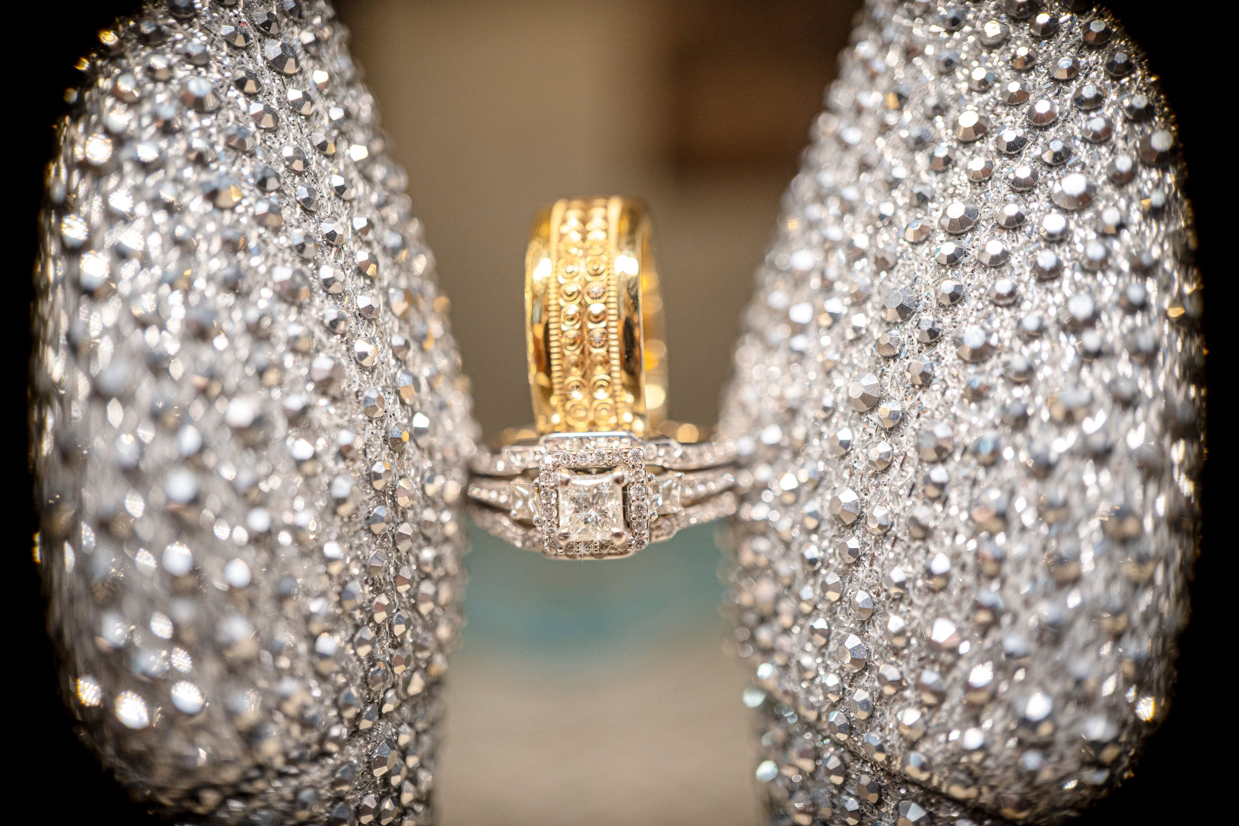 Wedding rings displayed between sparkling crystal shoes with elegant bokeh effects.