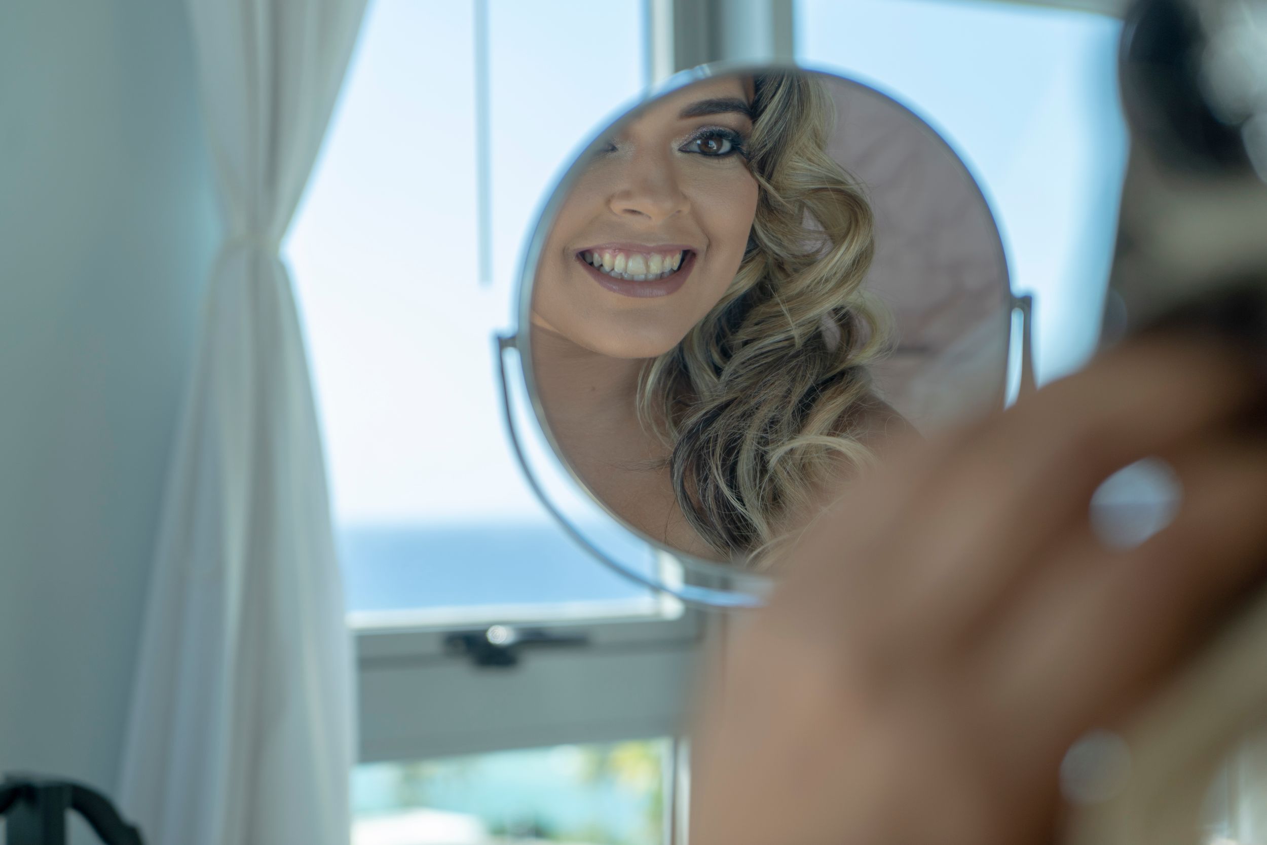 A blurred reflection of a smile in a small circular makeup mirror.
