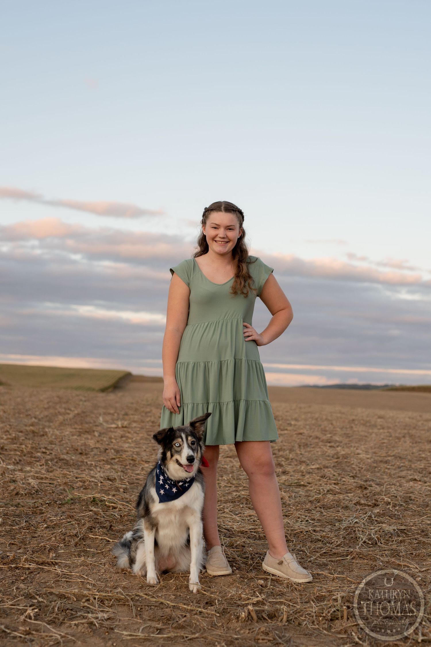 Portrait with a happy husky mix dog in a sage dress during sunset in an open field.