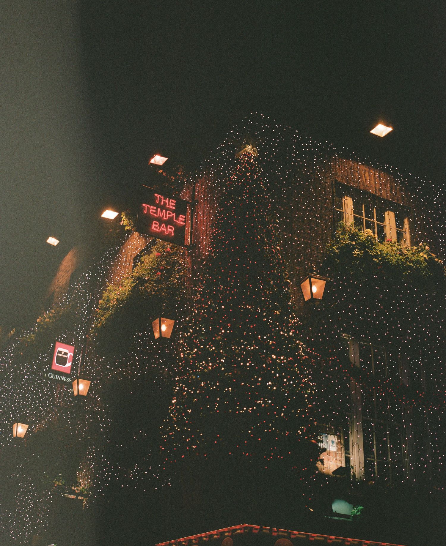 Historic building decorated with twinkling Christmas lights and lanterns at night.