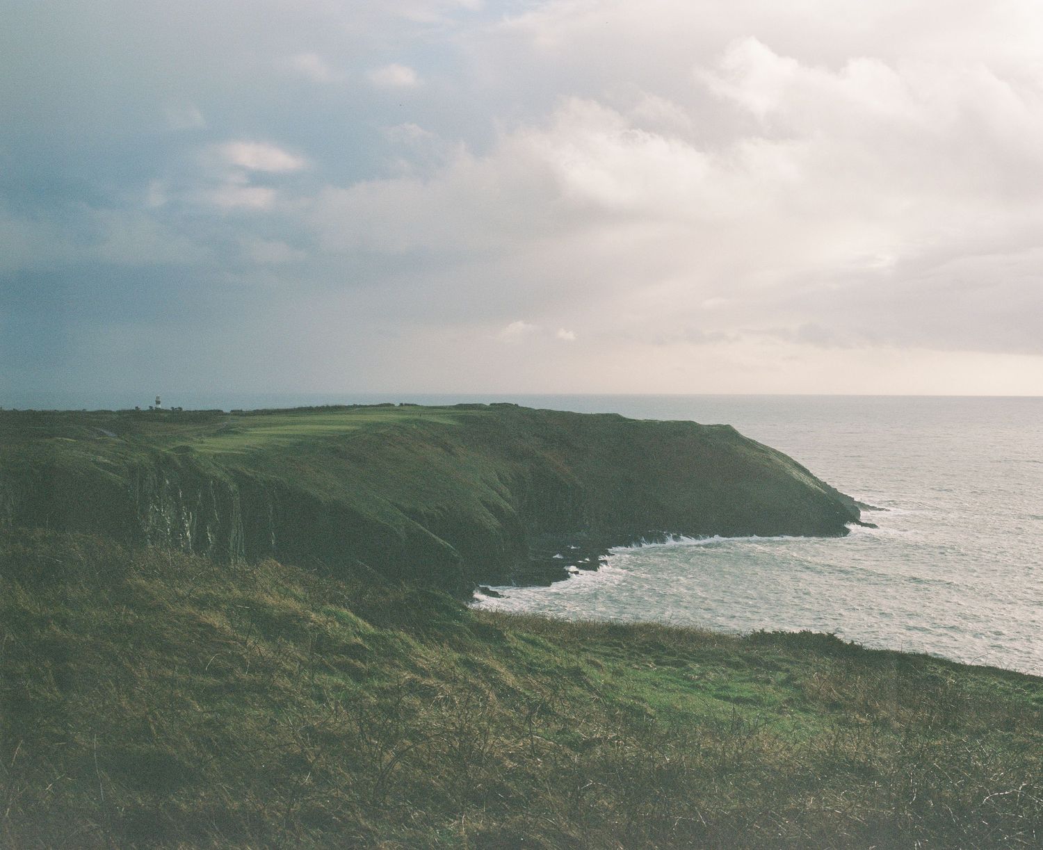 Dramatic coastal landscape with green cliffs dropping into the ocean.