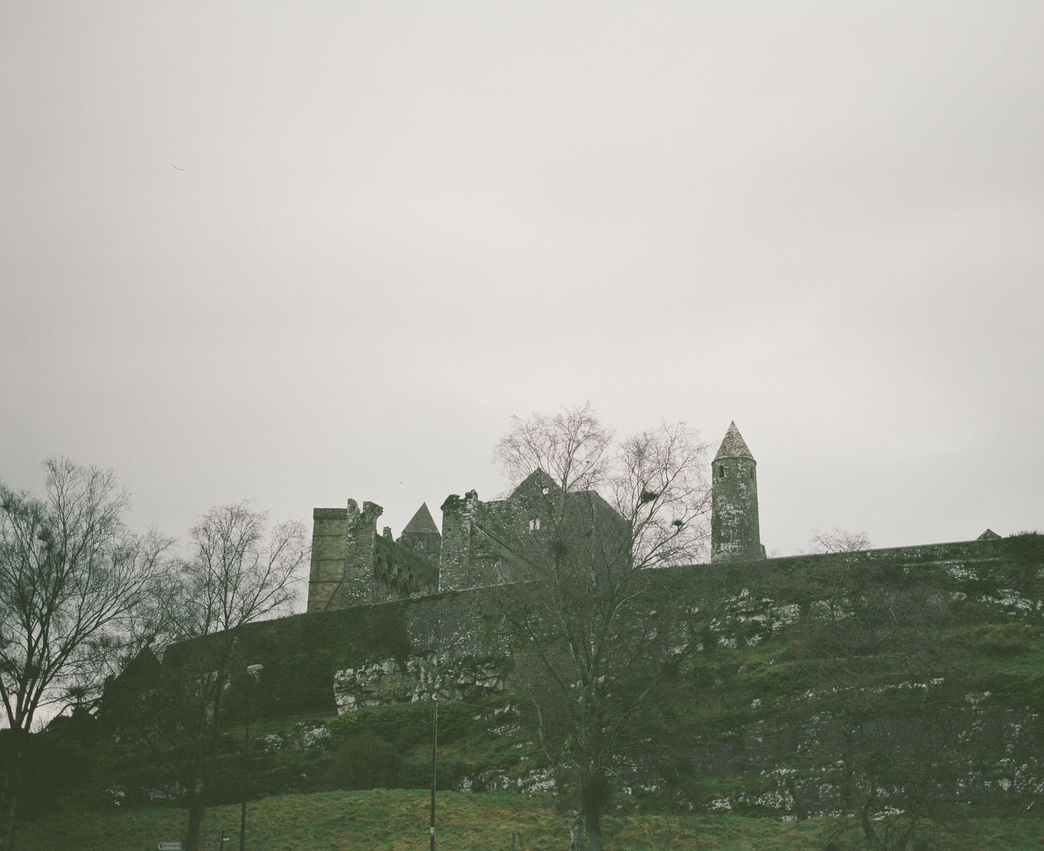 Ancient castle silhouette on a hilltop against an overcast sky.