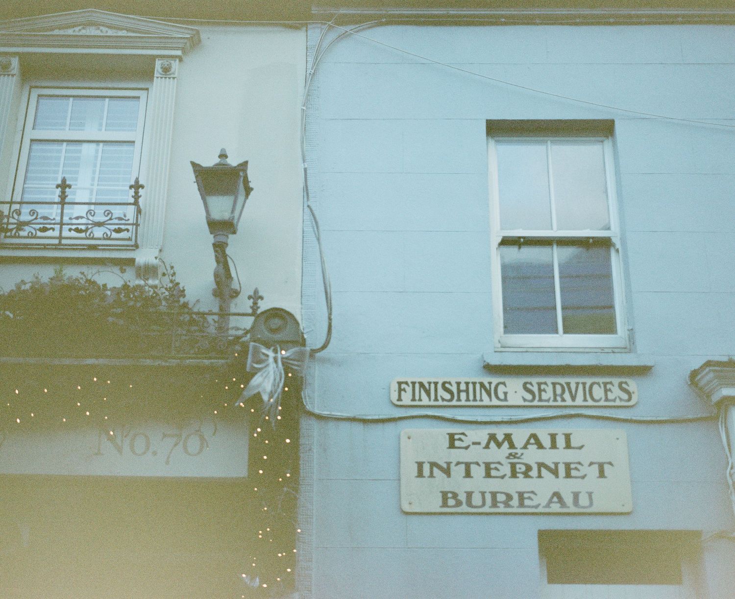Victorian building facade with vintage lamp post and sign advertising email and internet services.