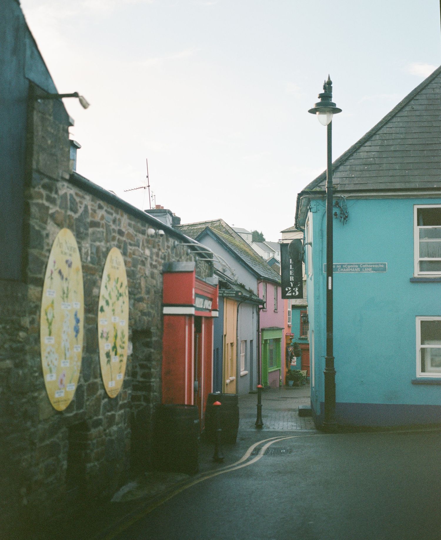 Colorful buildings line a narrow street in an Irish town with a vintage street lamp.