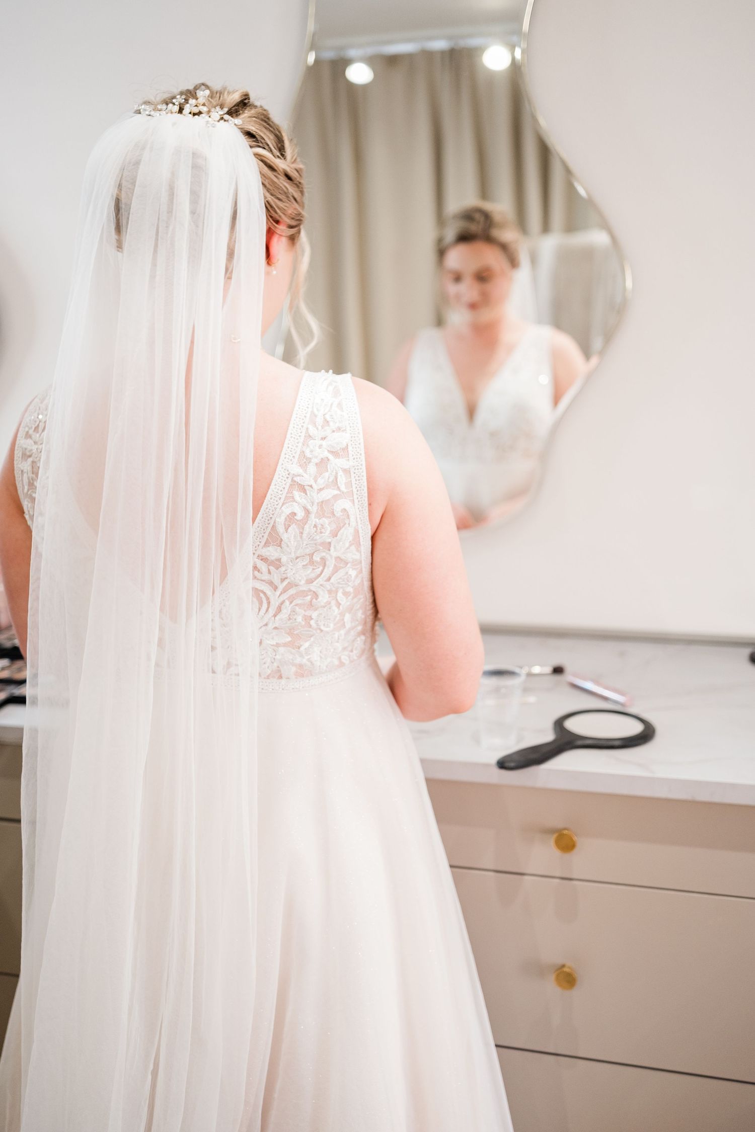 A bride admiring her wedding dress reflection in a stylish dressing room mirror.