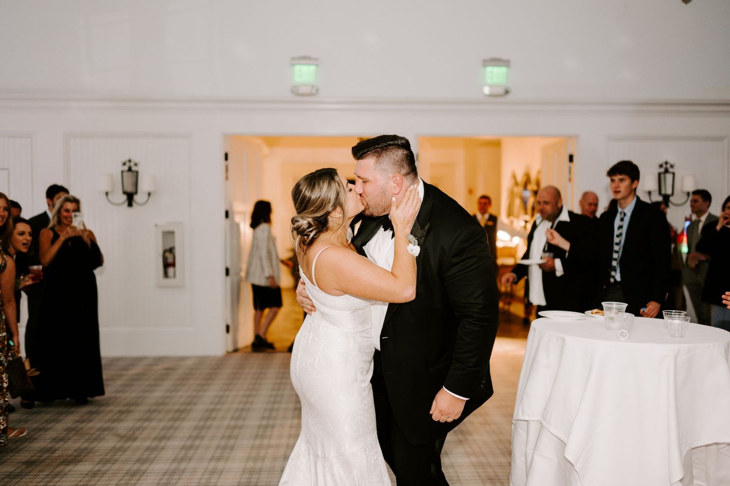 Newlyweds dancing energetically in an elegant white reception hall.