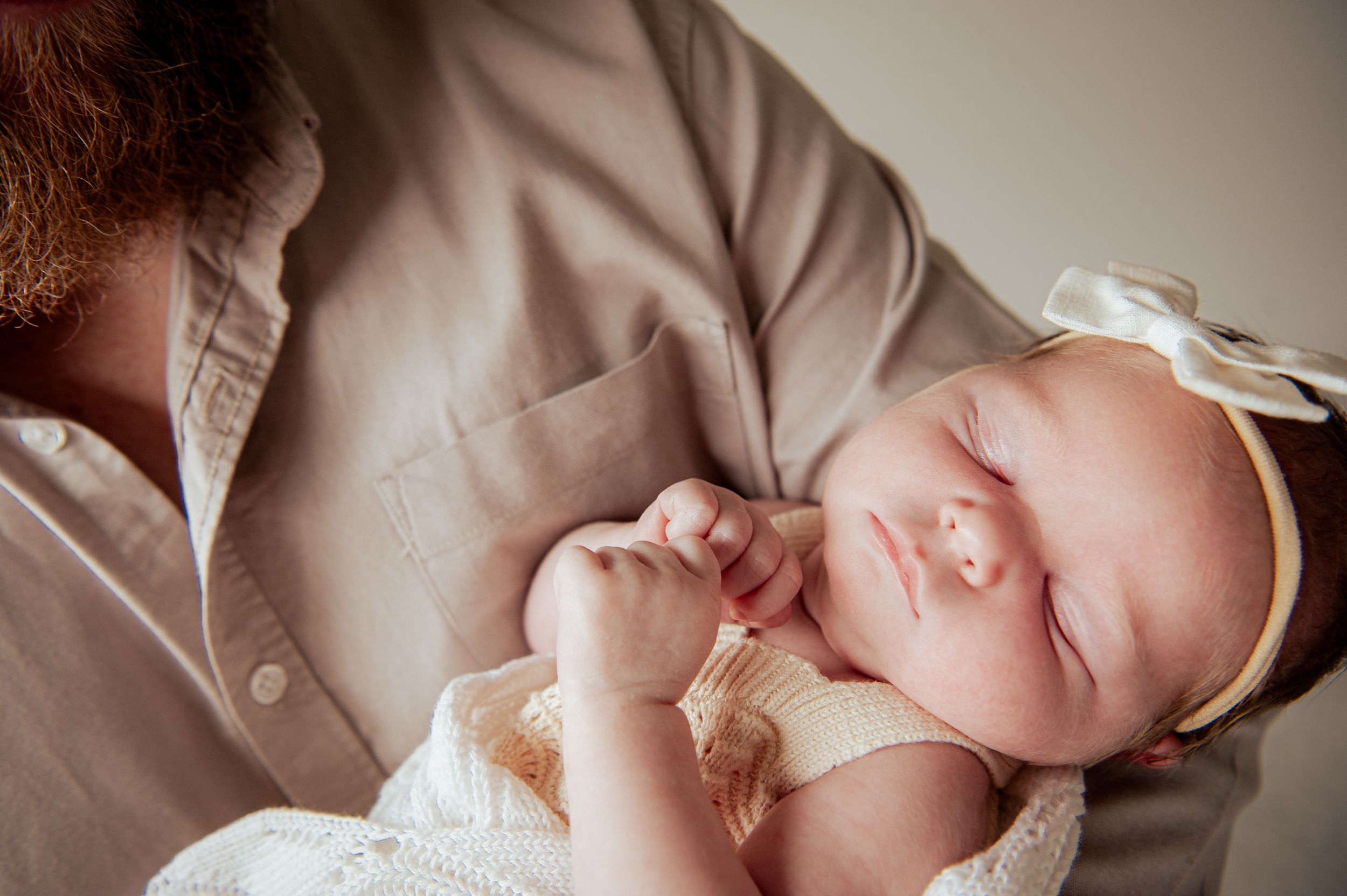 A newborn dressed in white clothing sleeps peacefully on a soft beige blanket.
Altona Family Photographer Melbourne