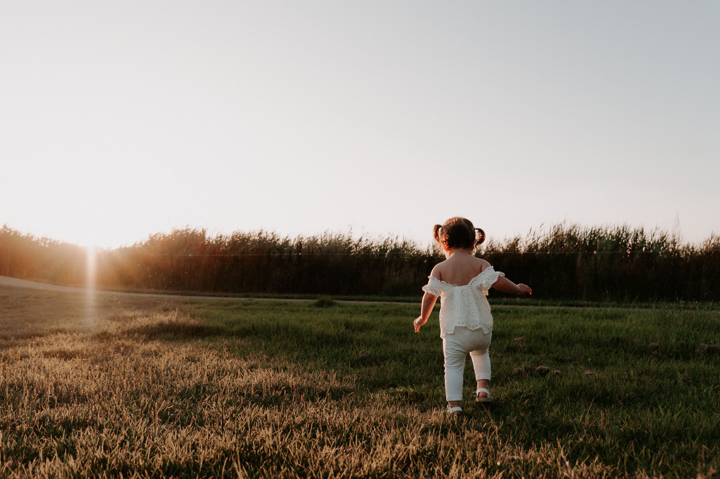 A child in white clothing runs through an open field during sunset.
Altona Family Photographer Melbourne