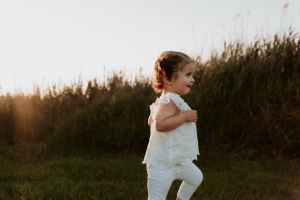 A toddler wearing all white plays joyfully in a sunlit meadow.
Altona Family Photographer Melbourne