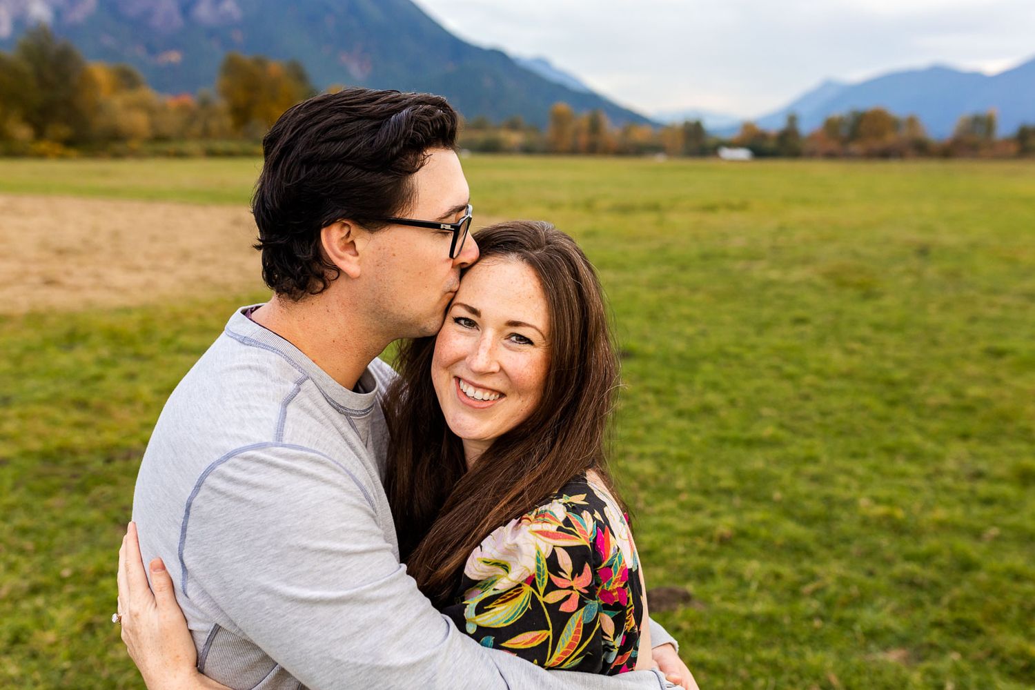Husband kissing wife tenderly at Meadowbrook Farm Preserve.