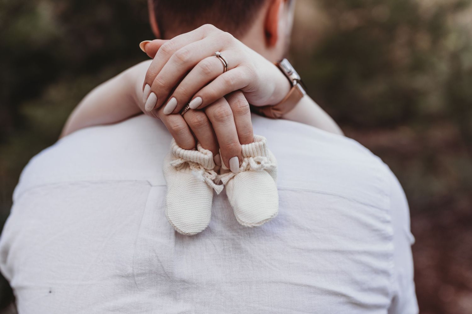 Mother to be holding baby shoes during maternity photoshoot
