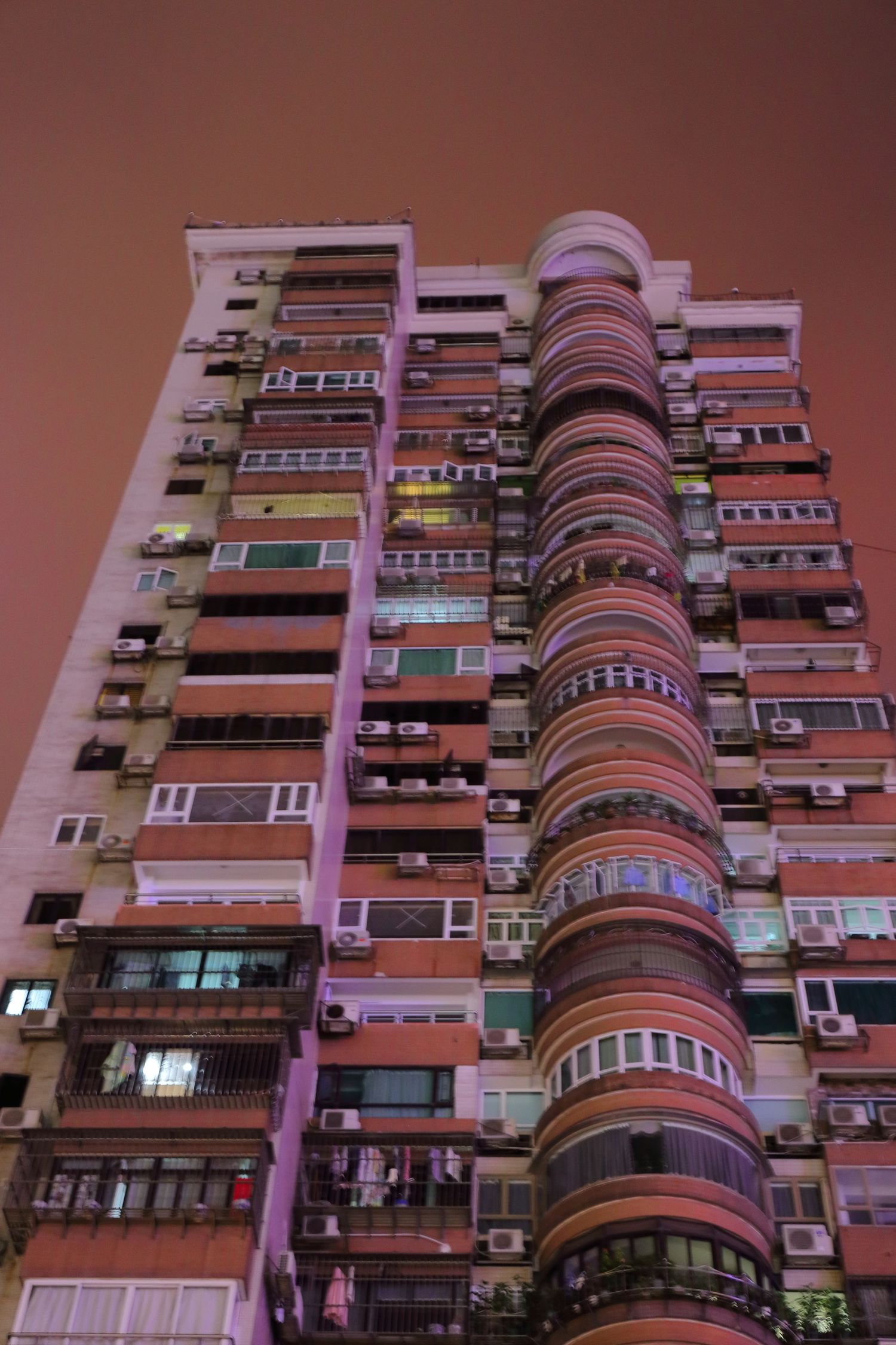 Pink-tinted high-rise apartment building with distinctive curved balconies in Macau.