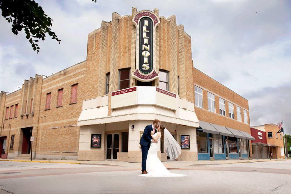 Newlyweds pose in front of a historic art deco theater with ornate architectural details.