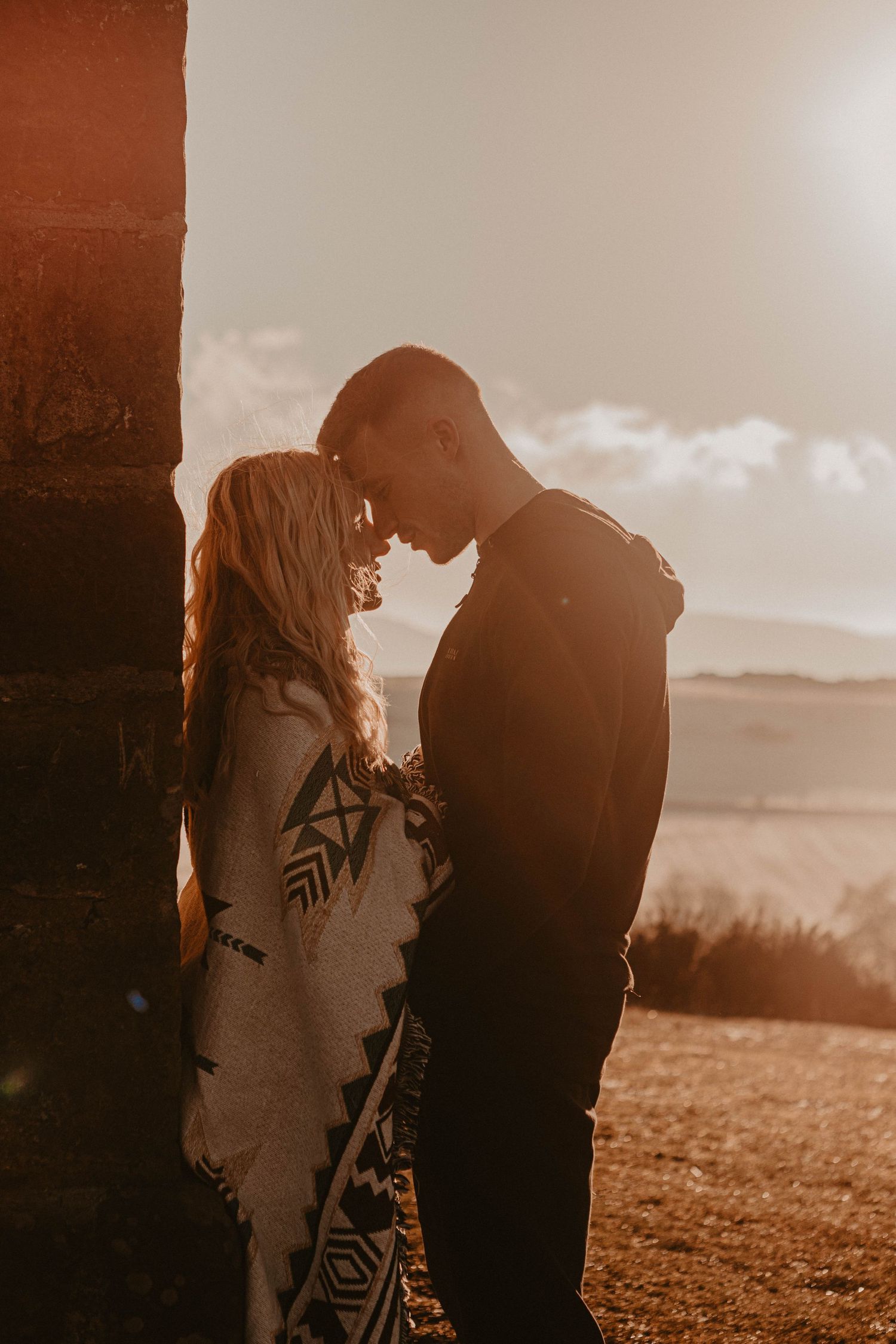 couple shot of them on their engagement shoot in a golden hour with sun rays hitting of them with their faces touching