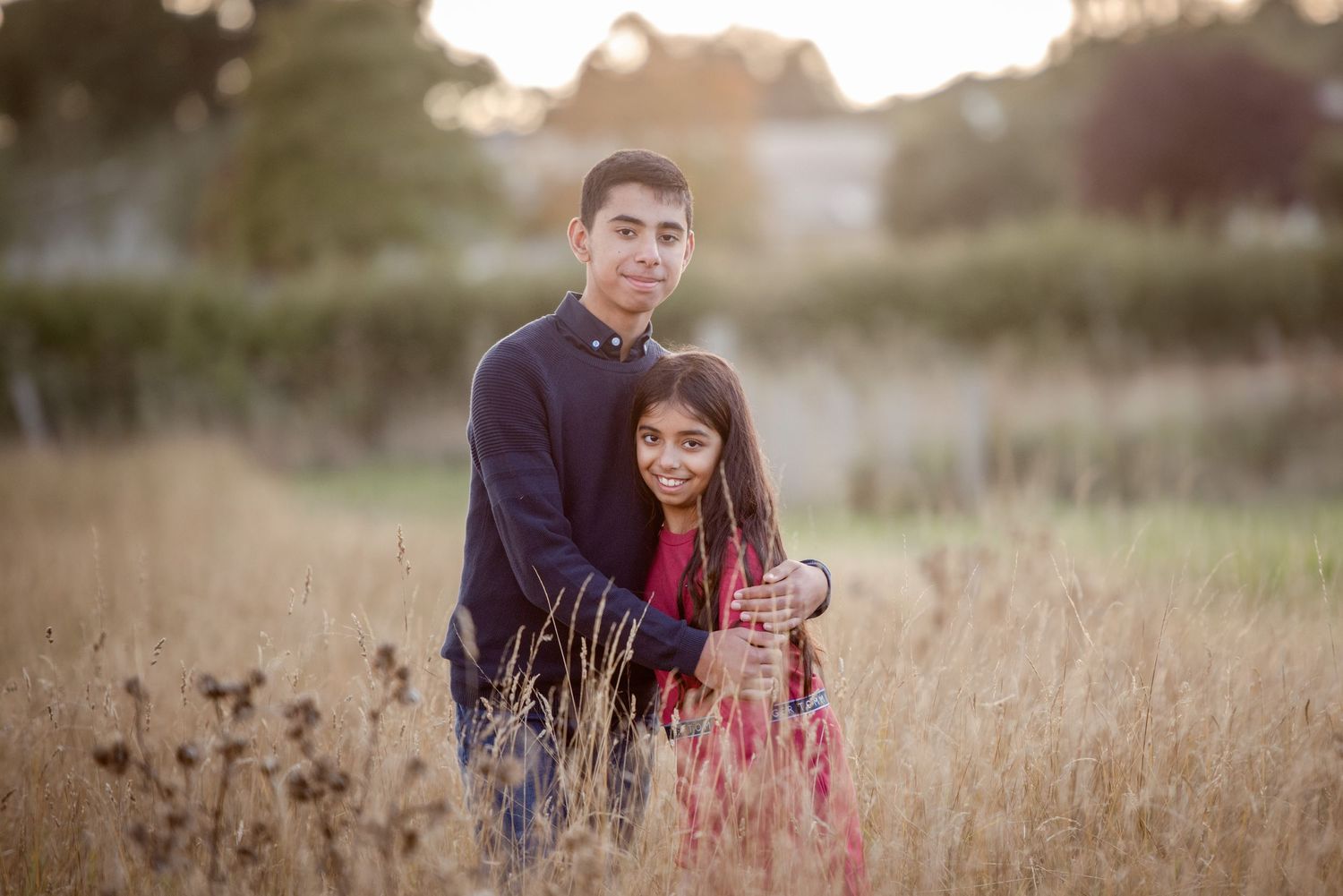A couple stands together in a field of wildflowers at dusk.