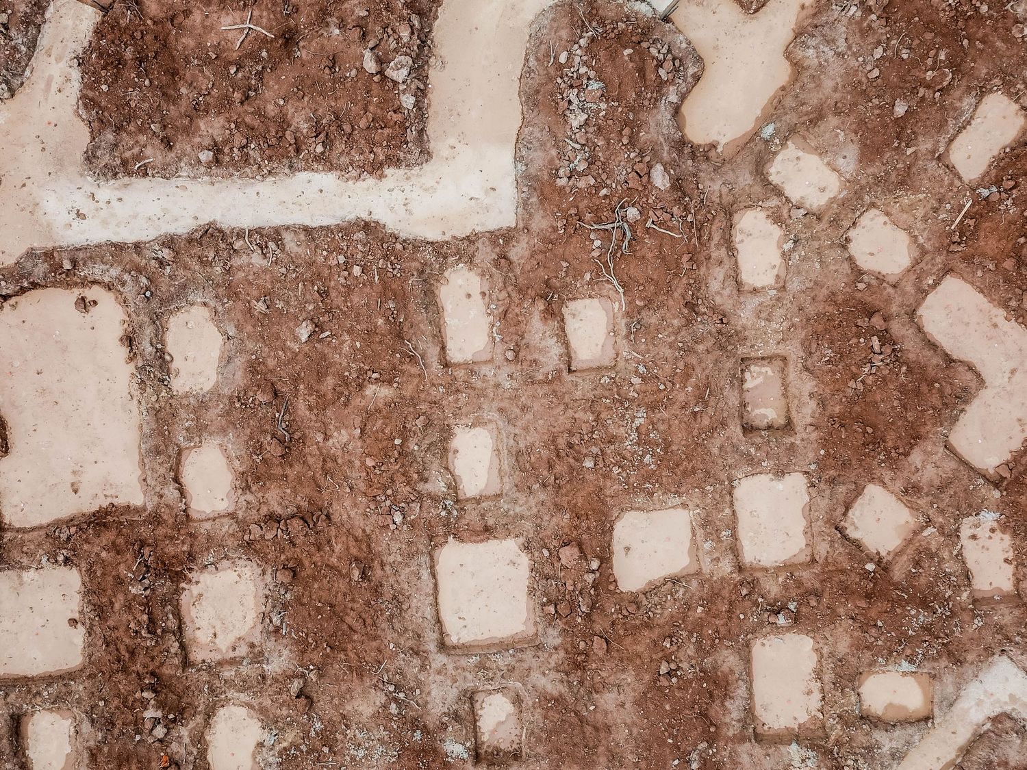 Close-up aerial view of white foundation markings on red soil showing room layouts.