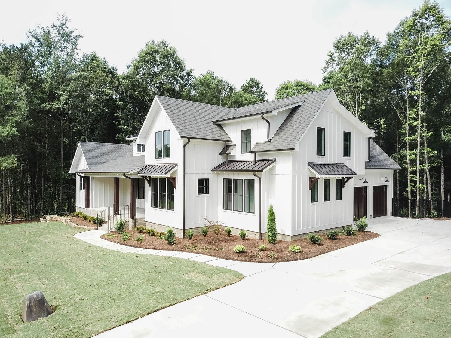 Elegant white modern farmhouse with gray roof and landscaped front yard.