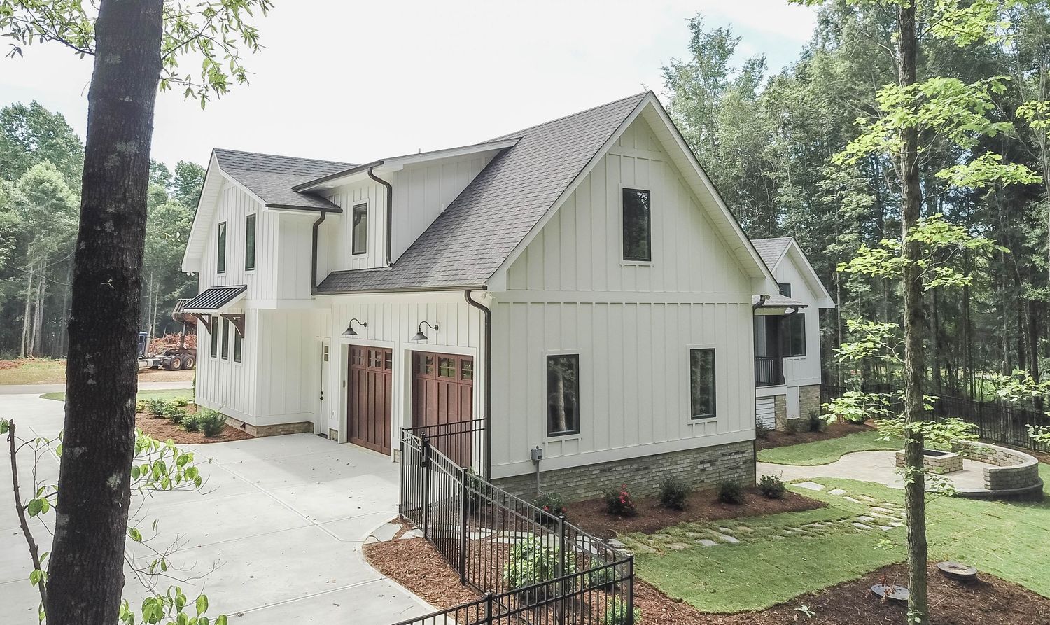 Side view of modern farmhouse displaying attached three-car garage with black doors.