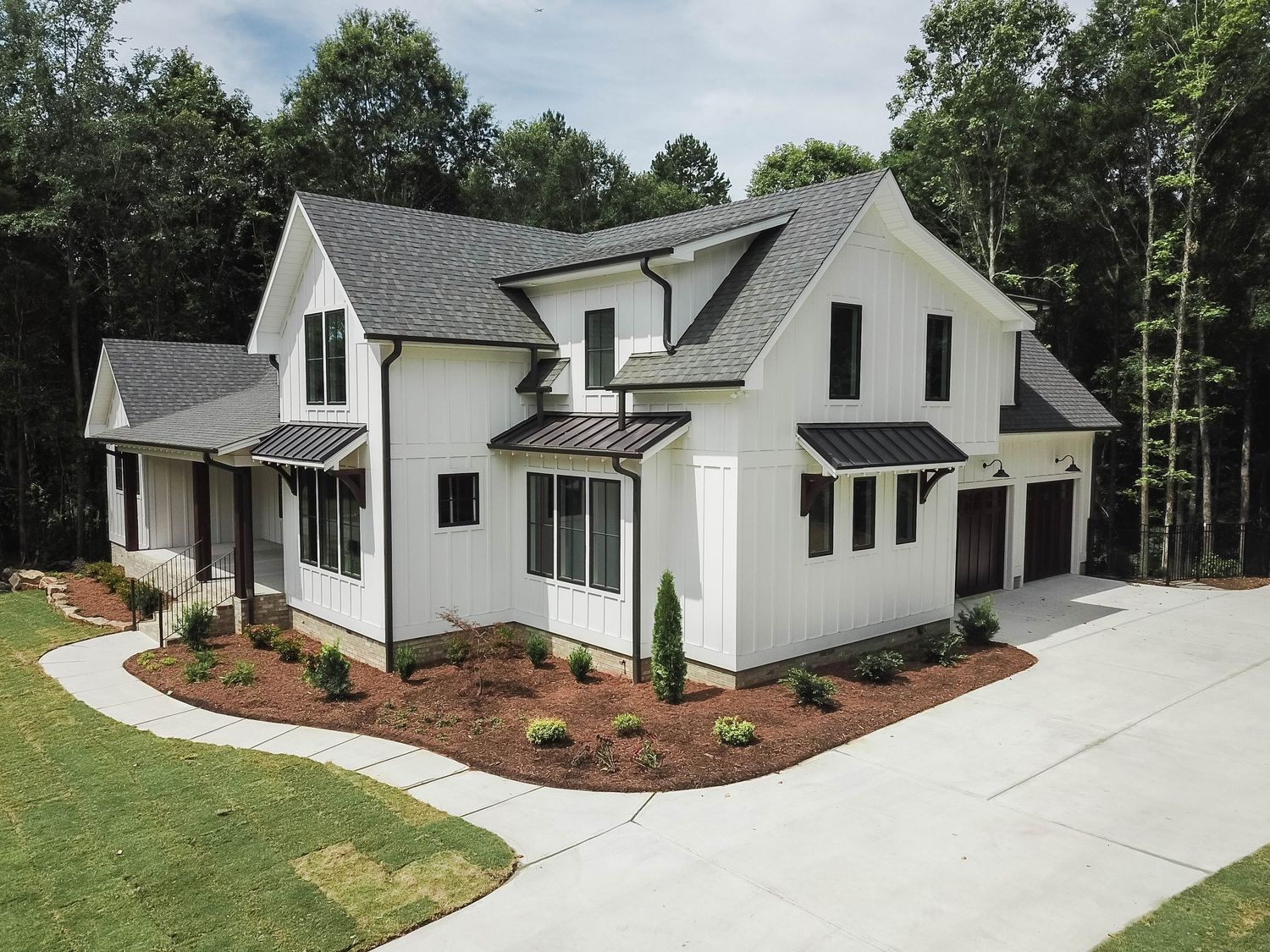 Contemporary farmhouse with black windows and architectural dormers viewed from front angle.
