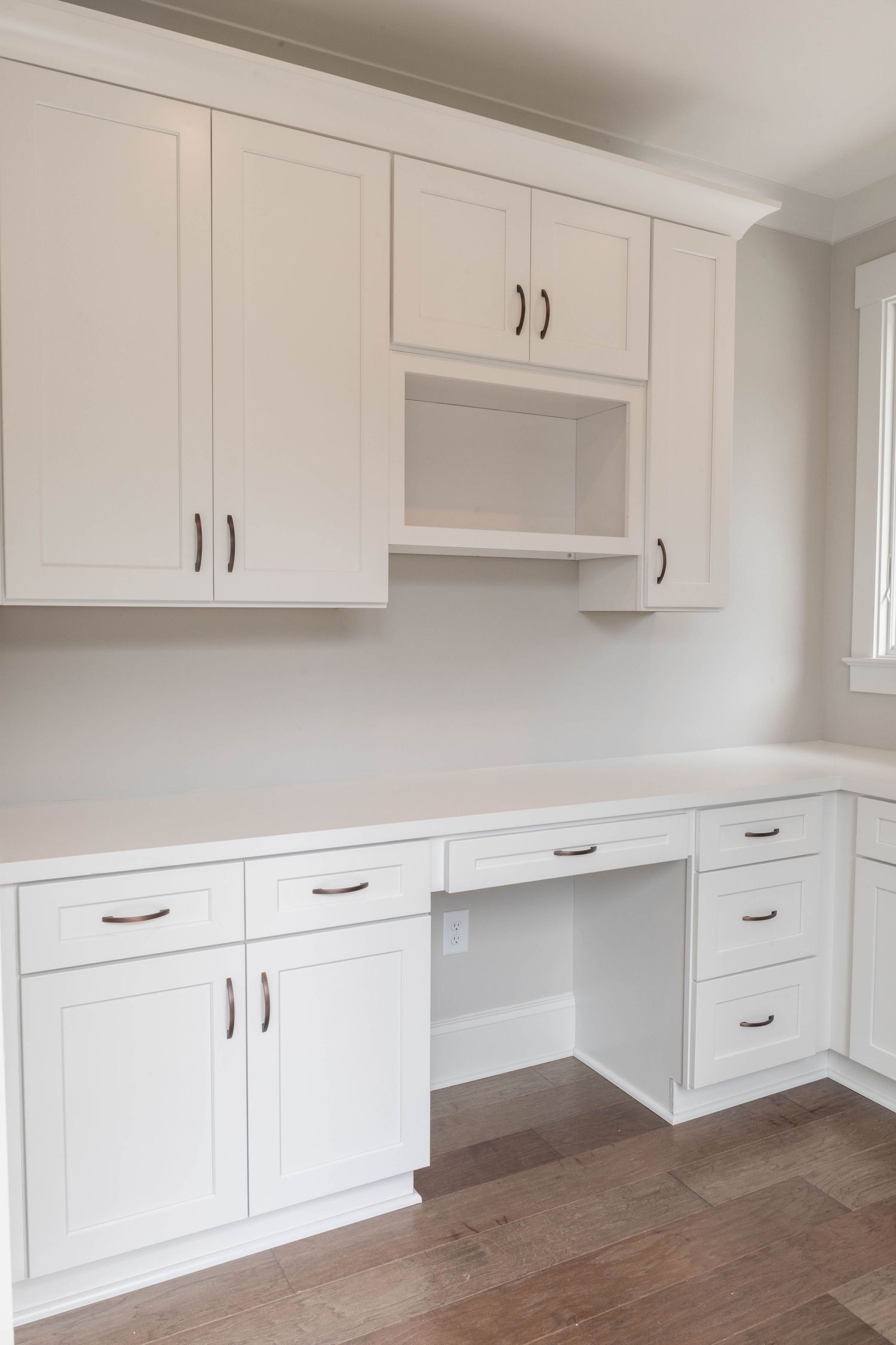 Built-in white desk area with storage cabinets, drawers, and open shelving.