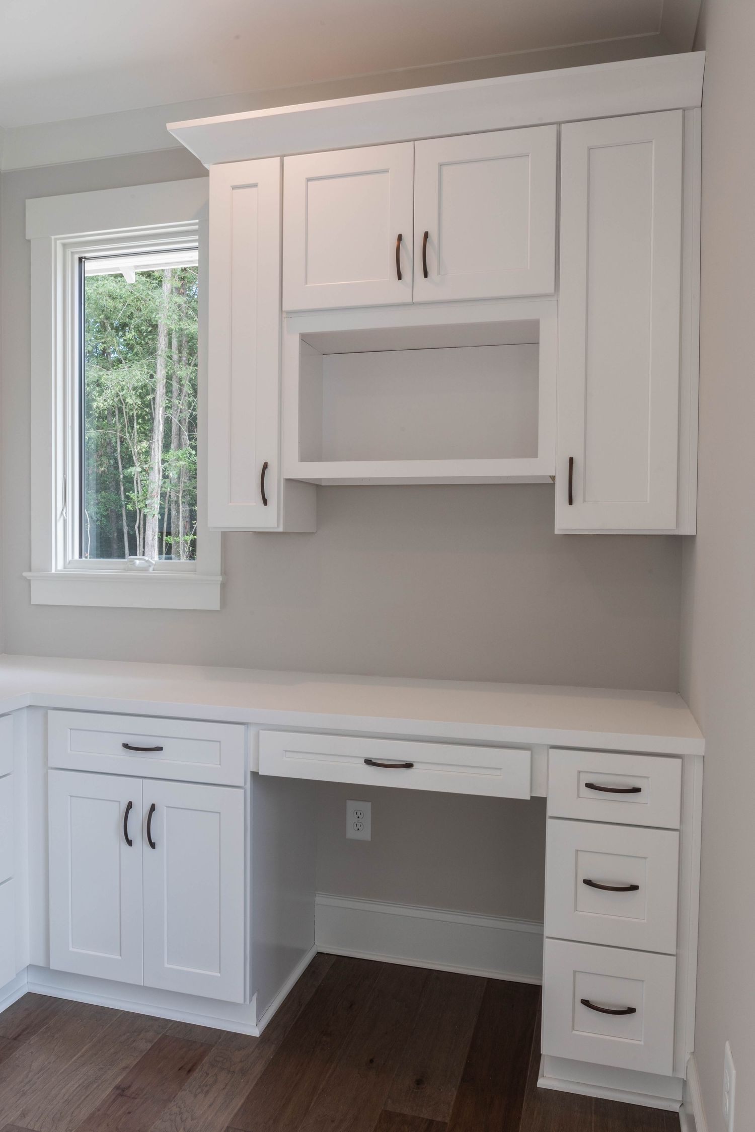 White built-in workstation with window view, upper cabinets, and drawers.