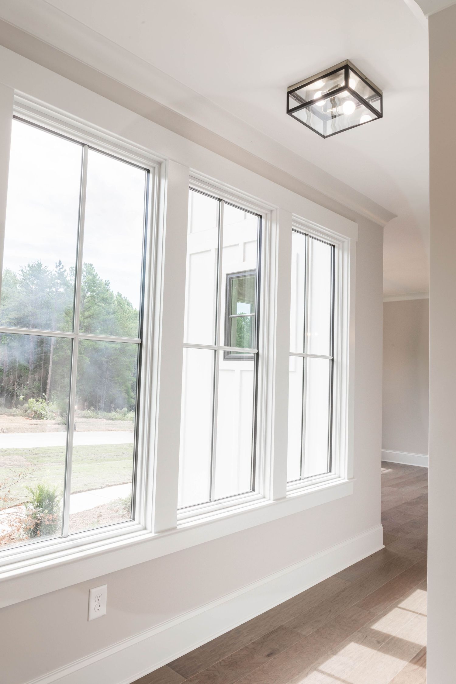 Modern interior featuring large triple-pane windows with colonial grids and hardwood floors.