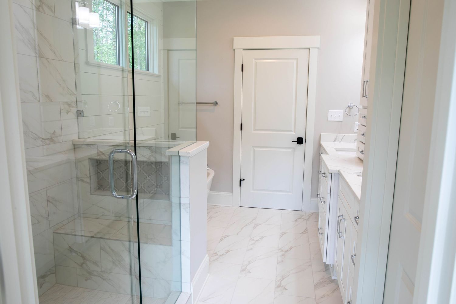 Luxurious marble bathroom featuring glass shower enclosure and modern white fixtures.