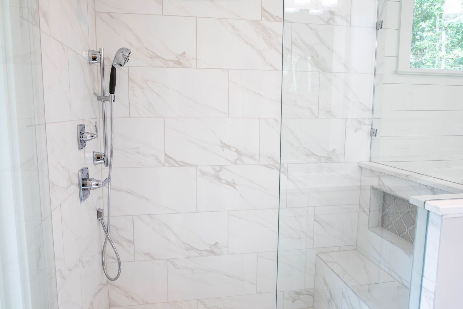 Marble shower interior with multiple shower heads and sleek chrome fixtures.