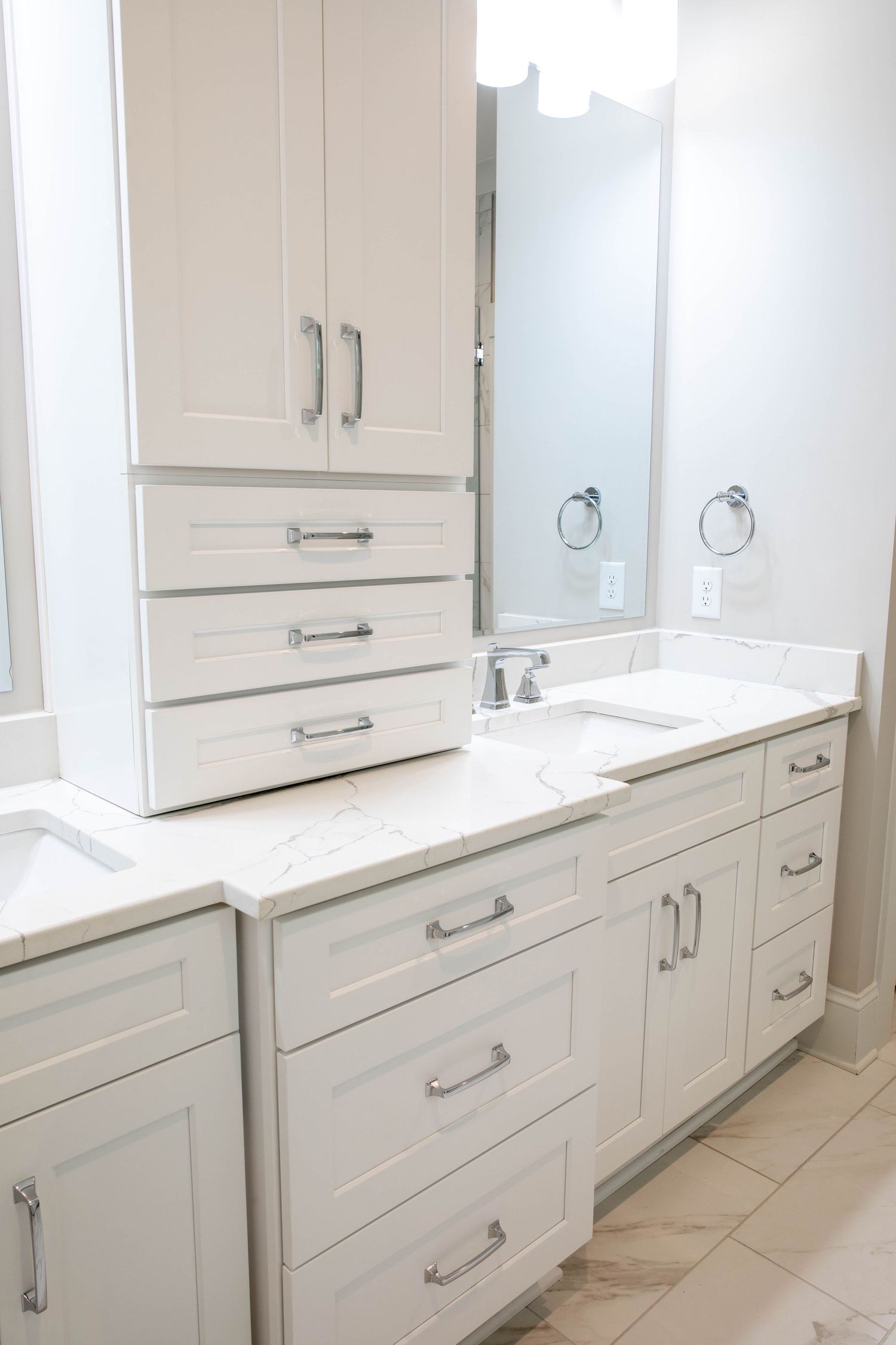 White bathroom vanity with marble countertop, multiple drawers and built-in storage cabinets.