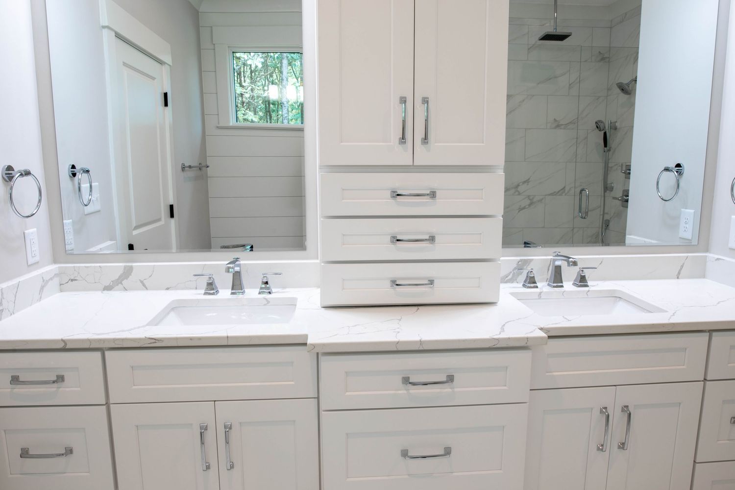 Modern white bathroom vanity with double sinks, marble countertops, and built-in storage cabinet.