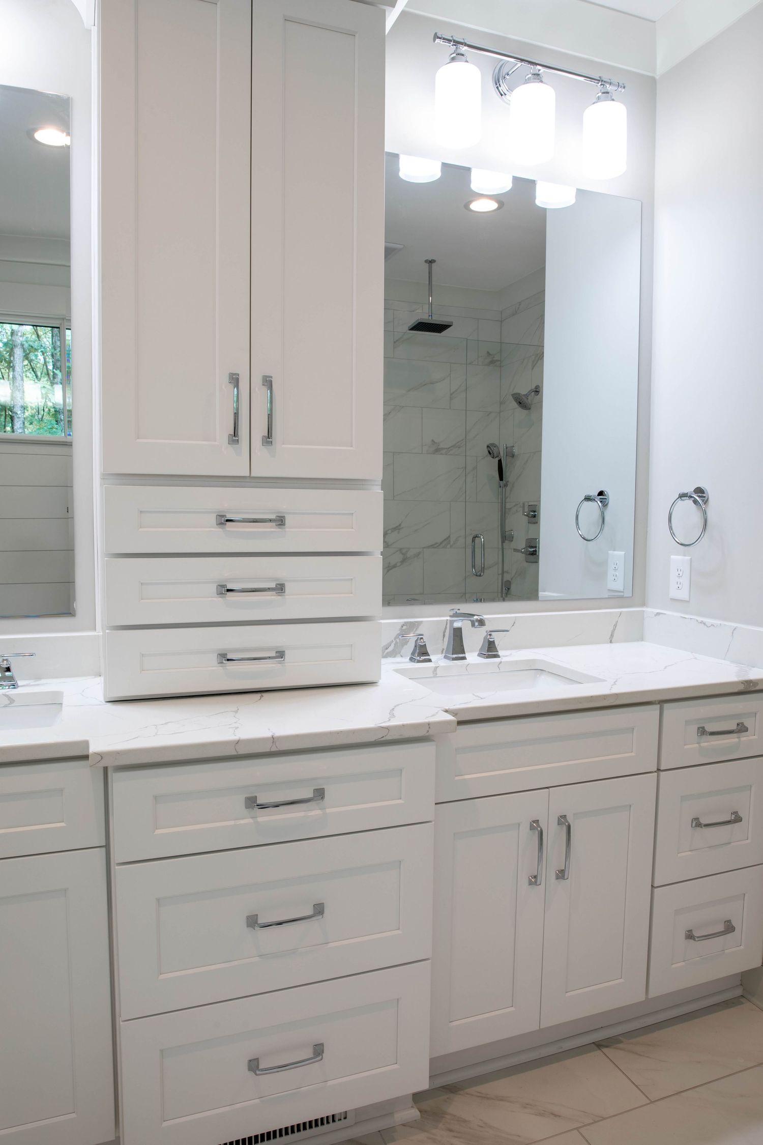 Luxurious double vanity bathroom with white cabinetry, marble tops, and modern chrome fixtures.