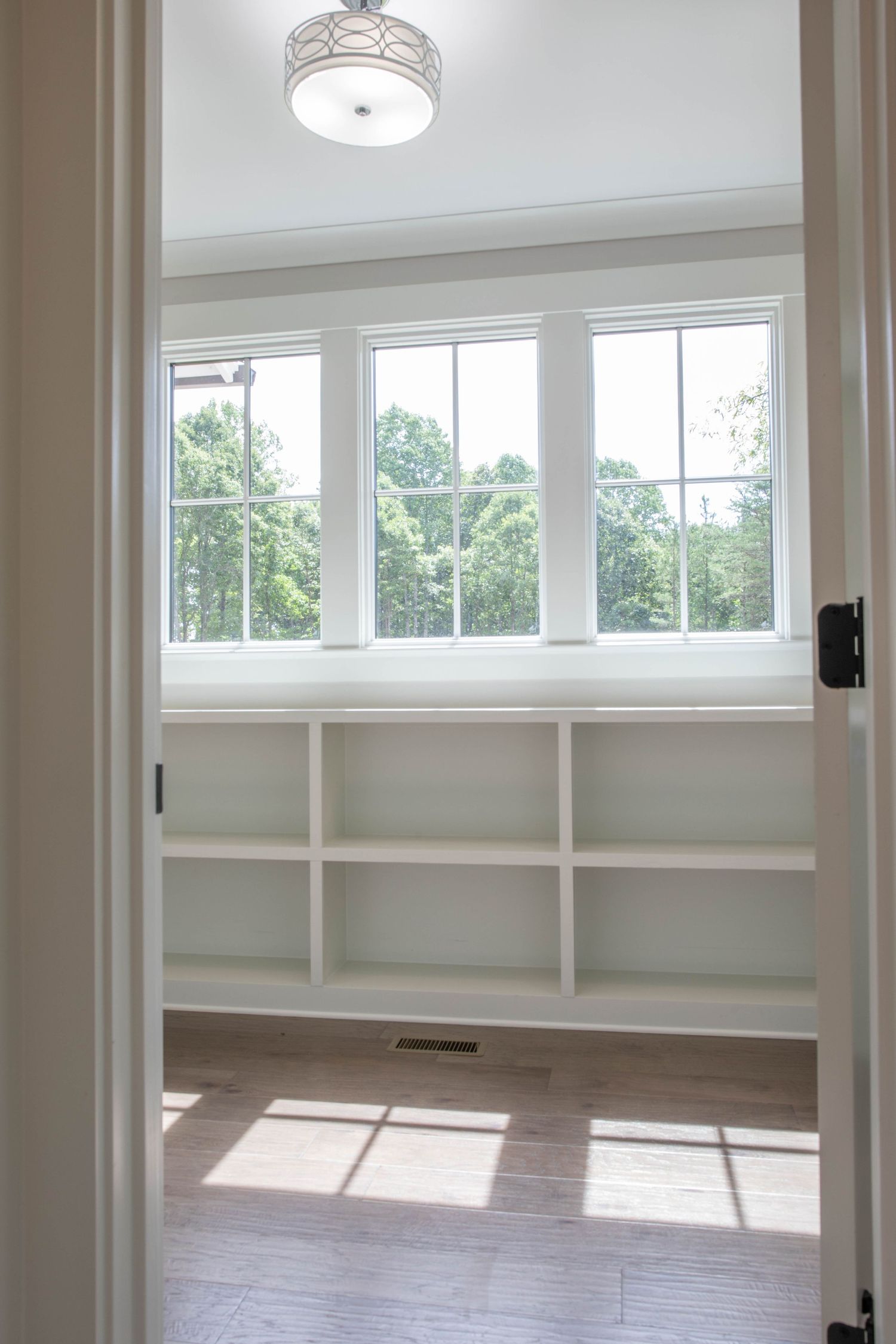 Bright room with large windows, built-in white shelving, and elegant ceiling light fixture.