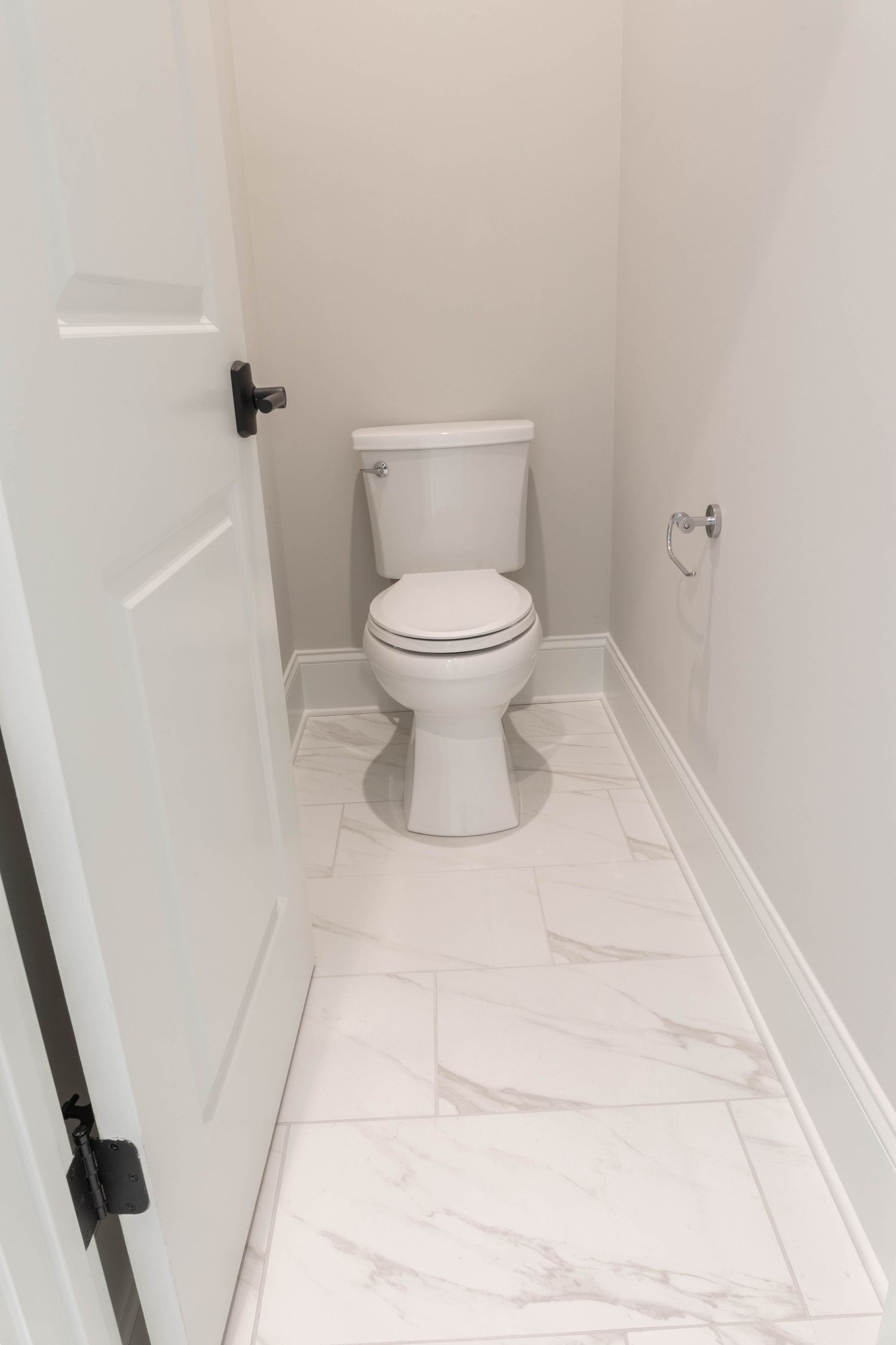 Small powder room with white marble tile flooring and modern toilet fixture.