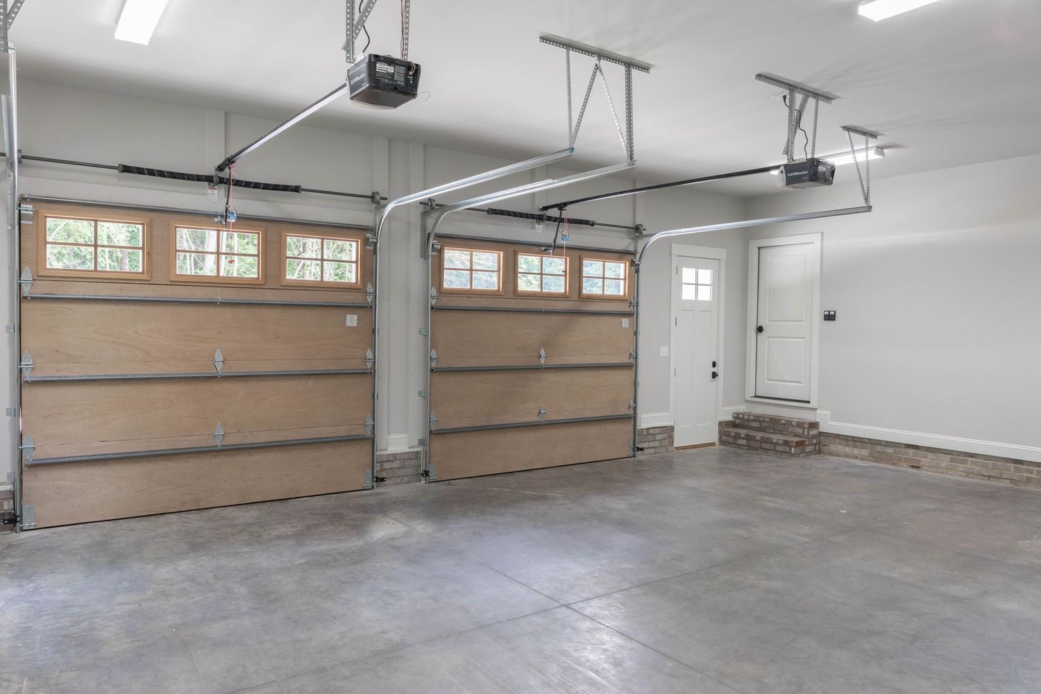 Spacious two-car garage with overhead doors, windows, and finished concrete floors.
