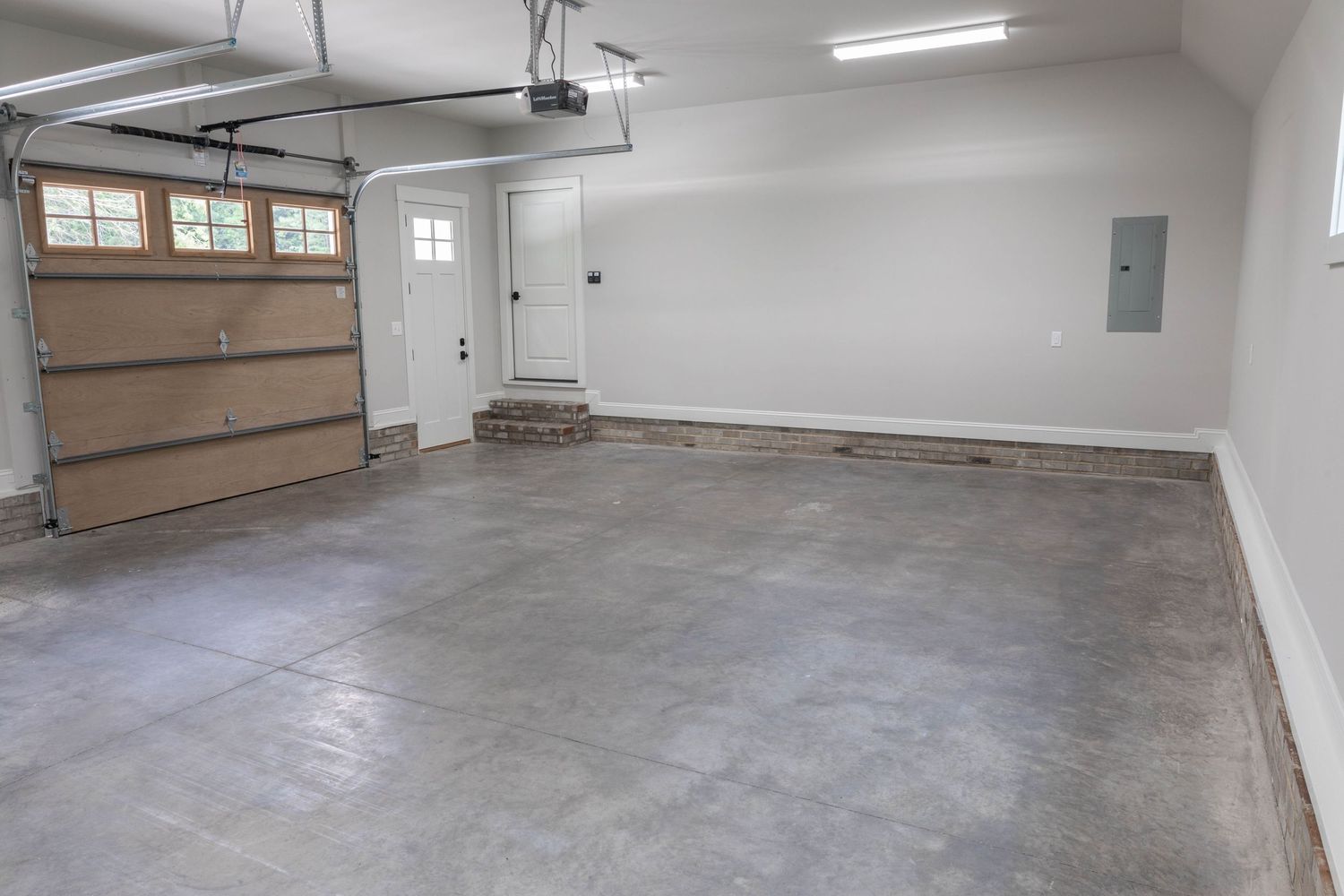 Modern garage interior showing concrete floor, storage solutions, and dual overhead doors.