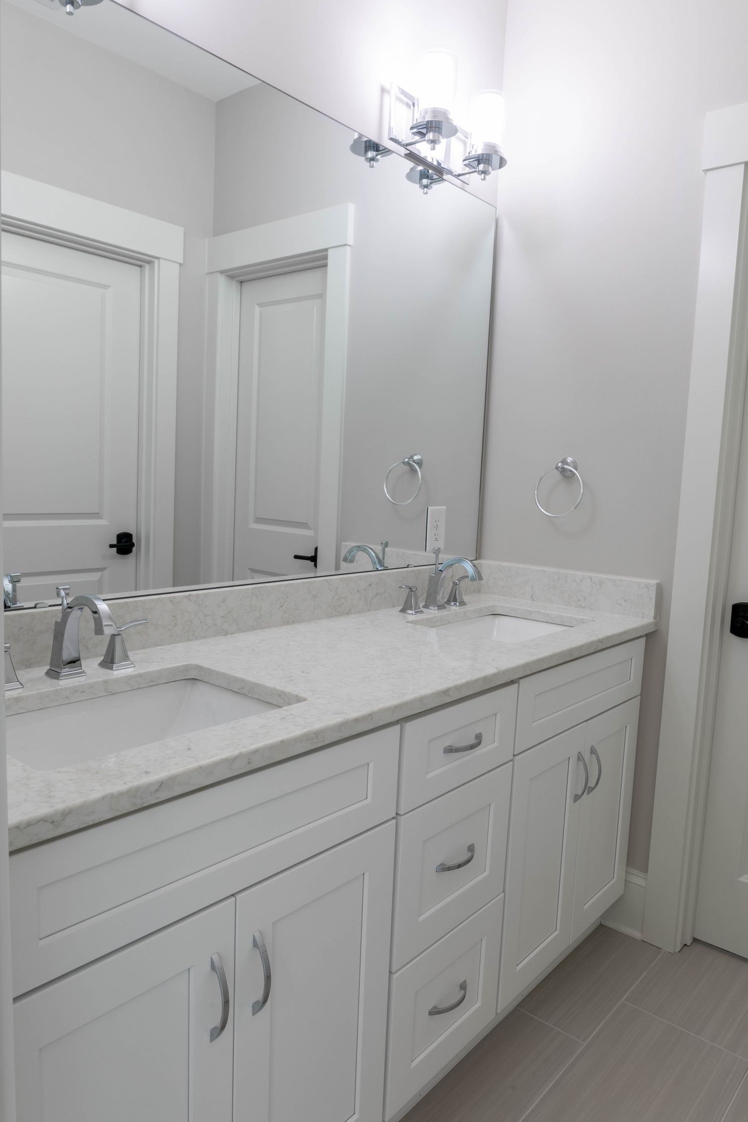 Modern white bathroom vanity with double sinks, marble countertop and chrome fixtures.