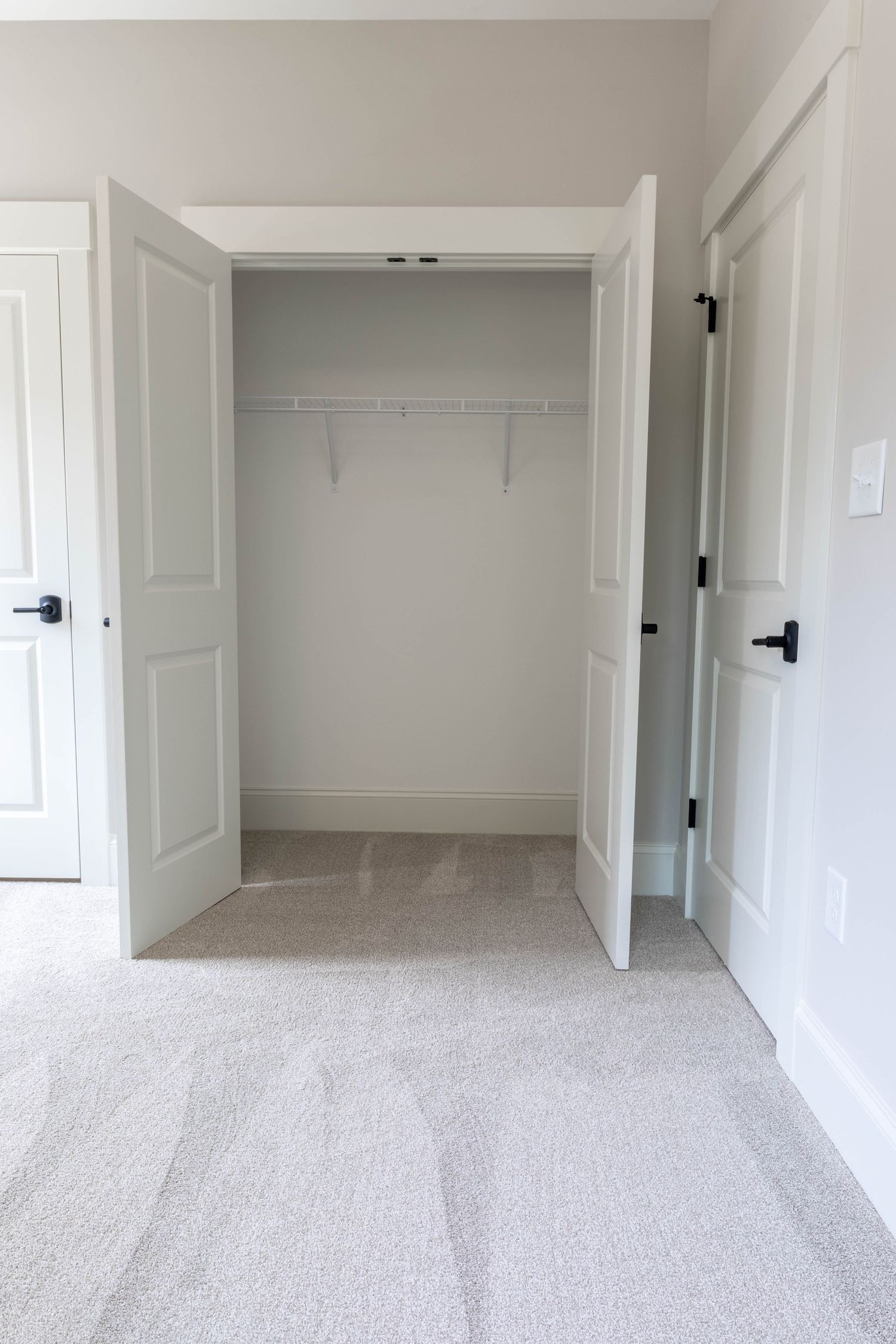 Spacious bedroom closet with white double doors and built-in wire shelving in a modern home.